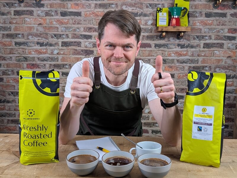 Barista giving thumbs up with coffee bags and cups
